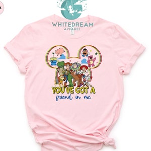 May include: Pink t-shirt with a Mickey Mouse head silhouette featuring Toy Story characters. The text "You've got a friend in me" is printed below the image.