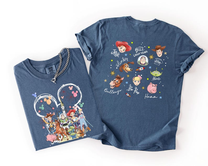 May include: Two blue t-shirts with Toy Story graphics. One shirt features a Mickey Mouse-shaped design with characters like Woody, Buzz Lightyear, and Jessie. The other shirt displays character faces and names like Slinky and Bo Peep.