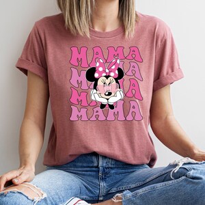 May include: A pink t-shirt with a graphic of Minnie Mouse wearing sunglasses and the text "MAMA" repeated four times in a retro font.