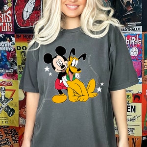 May include: A dark gray t-shirt with a cartoon image of Mickey Mouse and Pluto. Mickey Mouse is wearing red shorts and Pluto is wearing a green collar.