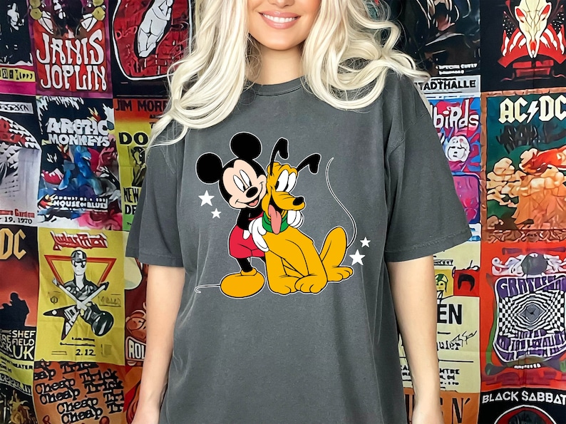 May include: A dark gray t-shirt with a cartoon image of Mickey Mouse and Pluto. Mickey Mouse is wearing red shorts and Pluto is wearing a green collar.