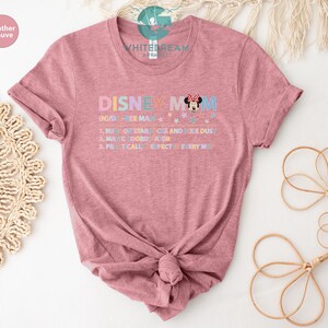 May include: A heather mauve t-shirt with the text "DISNEY MOM (NUDGE ME MAN) 1. RUN ON STARBUCKS AND PIXIE DUST 2. MAGIC COORDINATOR 3. PRACTICALLY PERFECT EVERY WAY" and a cartoon image of Minnie Mouse.