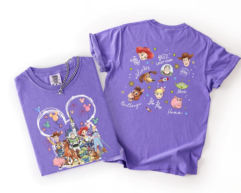 May include: Two purple t-shirts with Toy Story character graphics. One shirt features a Mickey Mouse head design with characters. The other shirt has character faces and names. A silver chain necklace is on one shirt.