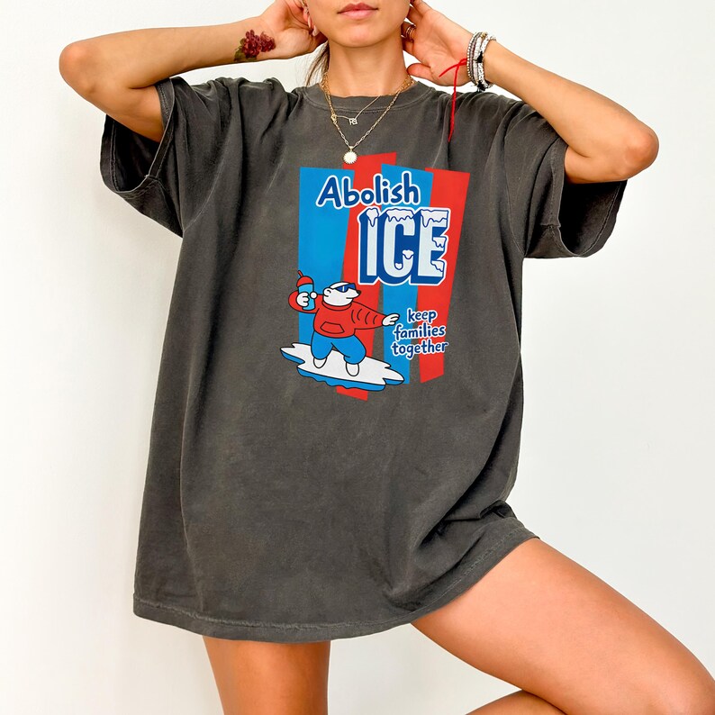 May include: Dark gray t-shirt with the text "Abolish ICE" in blue and white, and a cartoon image of a polar bear holding a popsicle. The shirt also includes the phrase "keep families together".