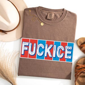 以下が含まれることがあります： 赤、白、青のデザインで「FUCKICE」という文字が入った茶色のTシャツ。 シャツは平らに置かれ、金のネックレス、ベージュの帽子、茶色のサンダルが添えられています。 シャツのサイズはXLです。