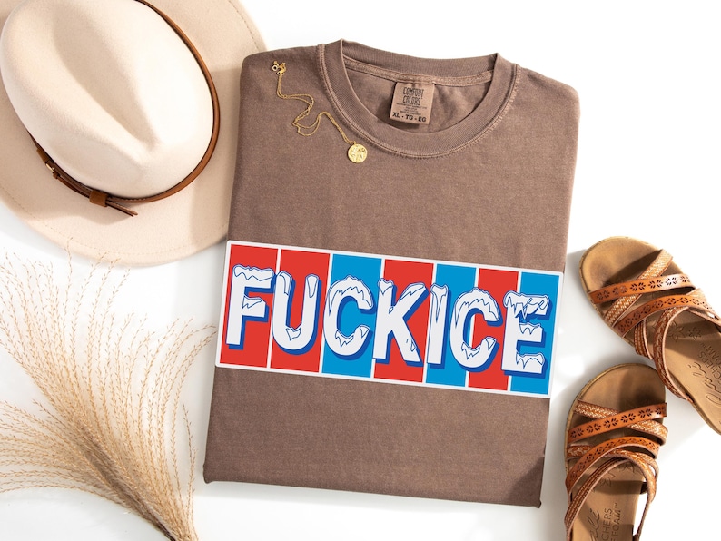 以下が含まれることがあります： 赤、白、青のデザインで「FUCKICE」という文字が入った茶色のTシャツ。 シャツは平らに置かれ、金のネックレス、ベージュの帽子、茶色のサンダルが添えられています。 シャツのサイズはXLです。