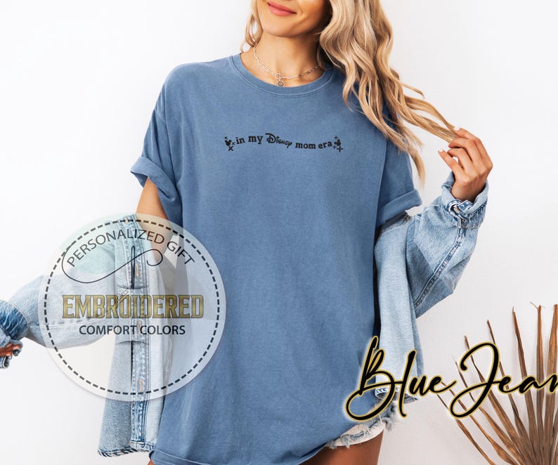 May include: A blue t-shirt with the text "In my Disney mom era" printed on the front.