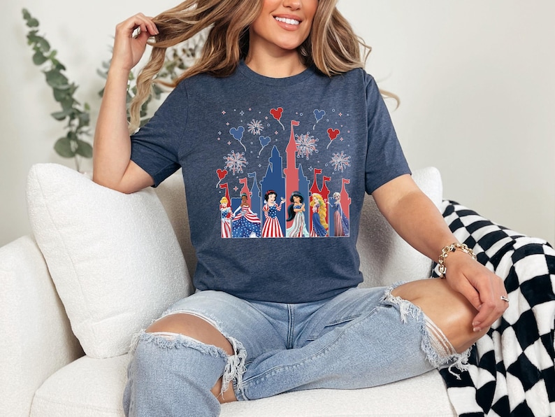 K&ouml;nnte beinhalten: Marineblaues T-Shirt mit patriotischem Schlossdesign, Feuerwerk und Zeichentrickfiguren in Rot, Wei&szlig; und Blau. Ideal f&uuml;r nationale Feiern, das Shirt aus weichem Material ist eine bequeme Wahl f&uuml;r Freizeitkleidung.