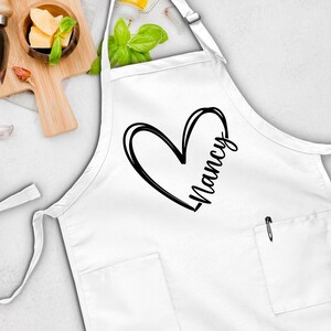 May include: White apron with a black heart and the name "Nancy" printed on it.