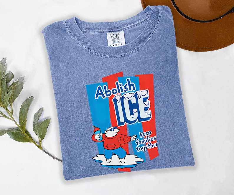 May include: A blue Comfort Colors t-shirt with a graphic that reads "Abolish ICE" in white and blue, with a cartoon polar bear holding a bottle. The text "keep families together" is also included.