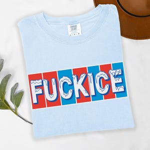 以下が含まれることがあります： 赤と青のストライプの背景に、白の「FUCKICE」の文字が青で縁取られた、水色のTシャツ。柔らかい素材でできており、クルーネックです。