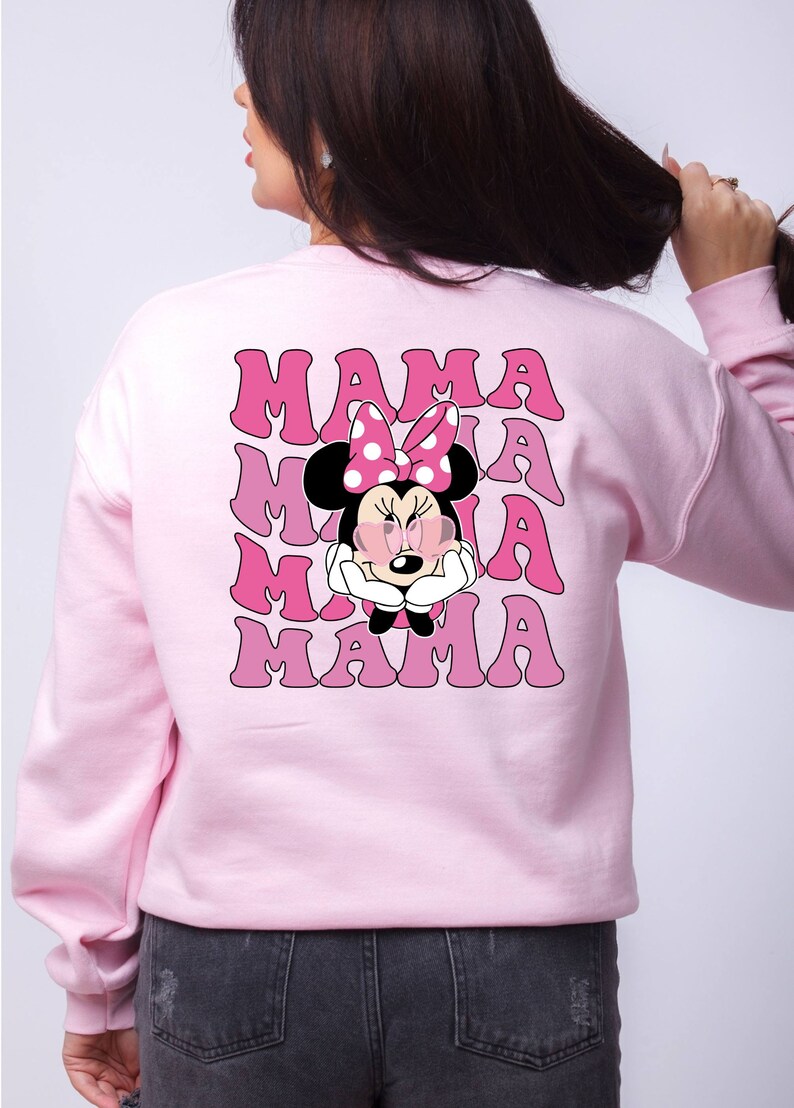 以下が含まれることがあります： ピンクのトレーナーに、サングラスとピンクのリボンをつけたミニーマウスのグラフィックがプリントされています。レトロなフォントで「MAMA」という文字が4回繰り返されています。