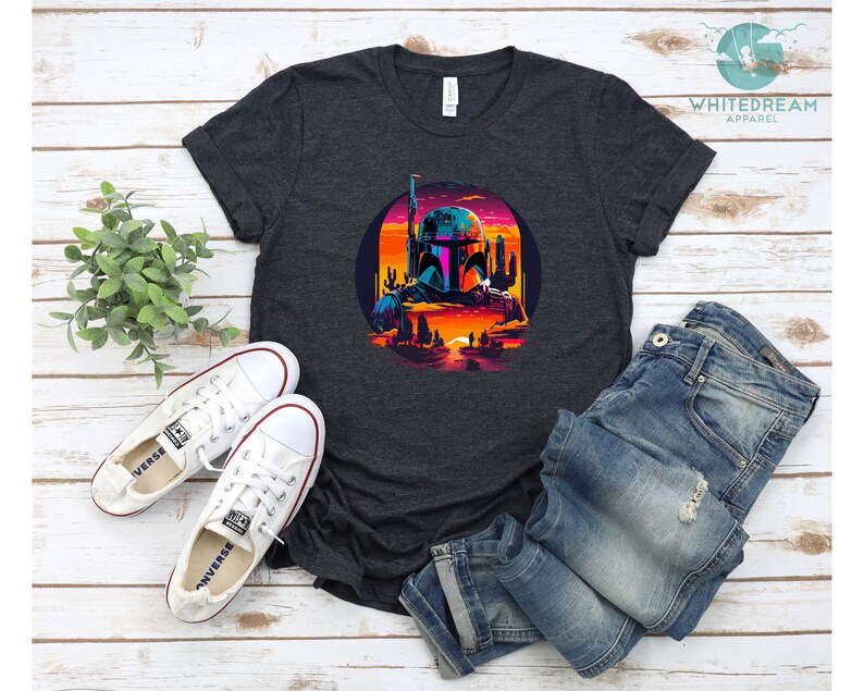 Pu&ograve; includere: Una t-shirt grigio scuro melange con una grafica retr&ograve; di Boba Fett in un paesaggio desertico. La grafica presenta un tramonto, cactus e una citt&agrave; futuristica.