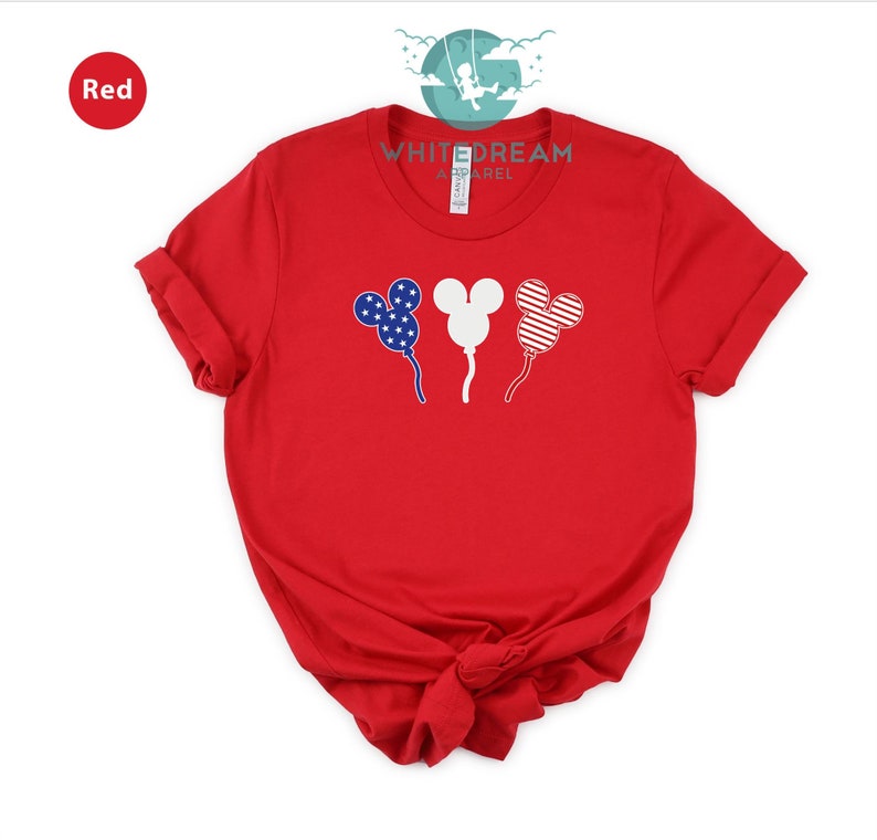 Puede incluir: Camiseta roja con un logotipo blanco "Whitedream Apparel" y tres globos con forma de Mickey Mouse con un dise&ntilde;o de bandera estadounidense.