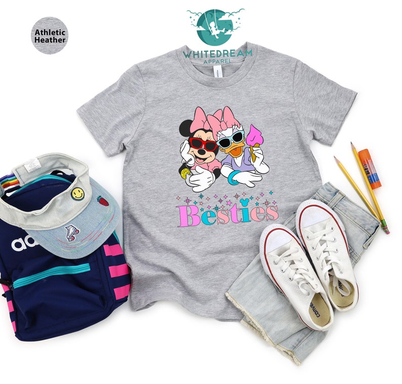 May include: A gray t-shirt with a graphic of Minnie Mouse and Daisy Duck wearing sunglasses and holding ice cream cones. The text "Bestie" is printed below the graphic in pink and blue letters.