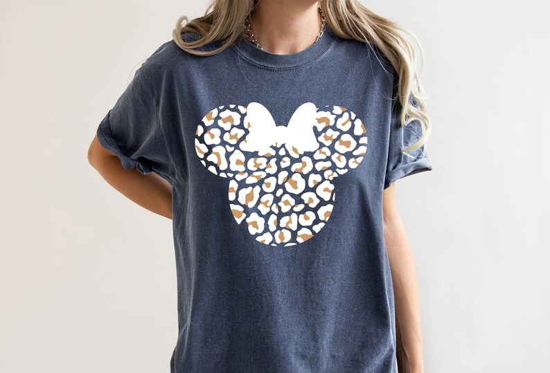 Peut inclure: Un t-shirt bleu fonc&eacute; avec un motif de t&ecirc;te de Minnie Mouse en imprim&eacute; l&eacute;opard blanc et marron.