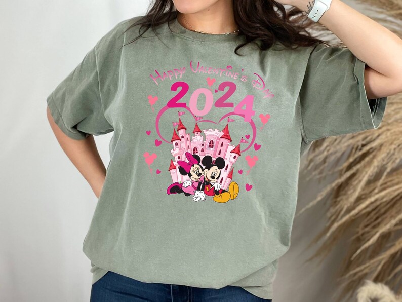 May include: Green t-shirt with a pink castle, Mickey Mouse and Minnie Mouse, and the text "Happy Valentine's Day 2024".