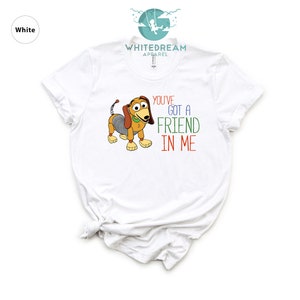 Op de afbeelding: Wit T-shirt met een cartoon afbeelding van een hond uit de Toy Story film. De tekst "You've got a friend in me" staat op het shirt gedrukt.