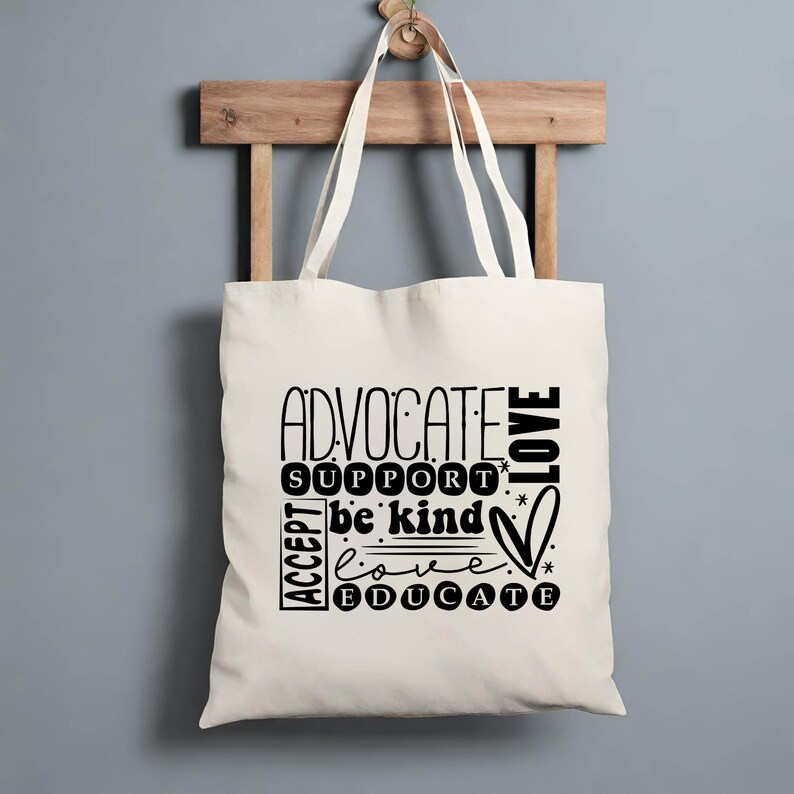 K&ouml;nnte beinhalten: Eine wei&szlig;e Stofftasche mit schwarzem Text, der "Advocate, Support, Be Kind, Love, Educate" lautet. Der Text ist kreisf&ouml;rmig mit einem Herzsymbol angeordnet.