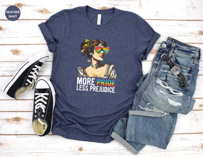 May include: A heather navy blue t-shirt with a graphic of a woman wearing rainbow sunglasses and the text "More Pride Less Prejudice".