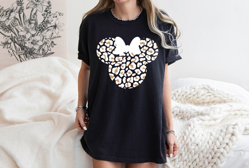 Peut inclure: T-shirt noir avec un motif de t&ecirc;te de Minnie Mouse en imprim&eacute; l&eacute;opard blanc et marron.