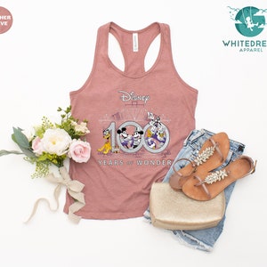 May include: A heather mauve tank top with a graphic of Mickey Mouse, Minnie Mouse, Donald Duck, and Goofy celebrating Disney's 100th anniversary. The graphic includes the text "Disney 100 Years of Wonder".