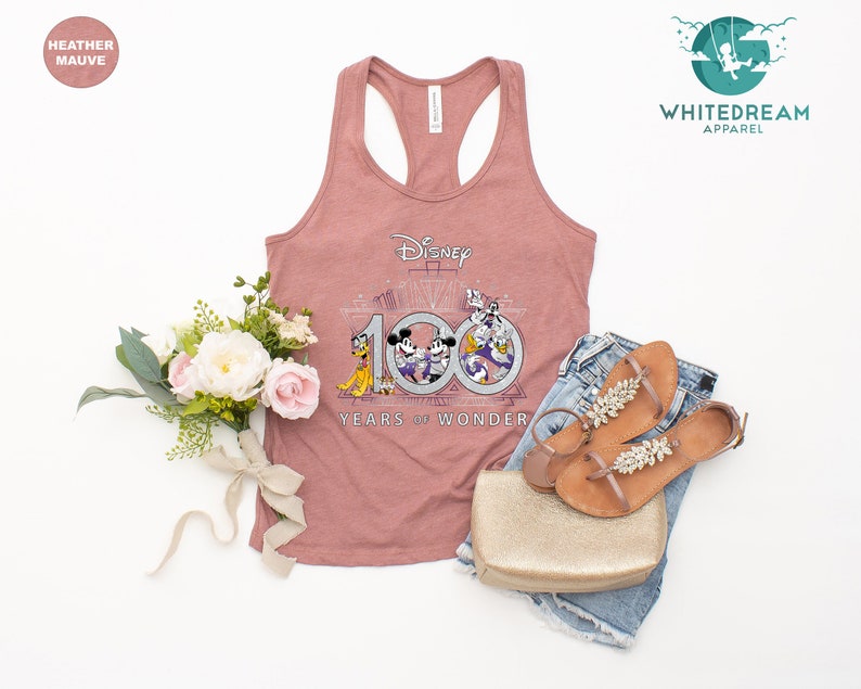 May include: A heather mauve tank top with a graphic of Mickey Mouse, Minnie Mouse, Donald Duck, and Goofy celebrating Disney's 100th anniversary. The graphic includes the text "Disney 100 Years of Wonder".