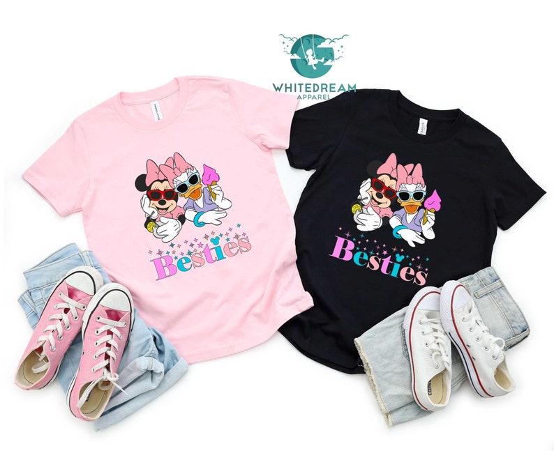 May include: Two pink and black t-shirts with a graphic of Minnie Mouse and Daisy Duck wearing sunglasses and holding ice cream cones. The text "Besties" is printed on both shirts.