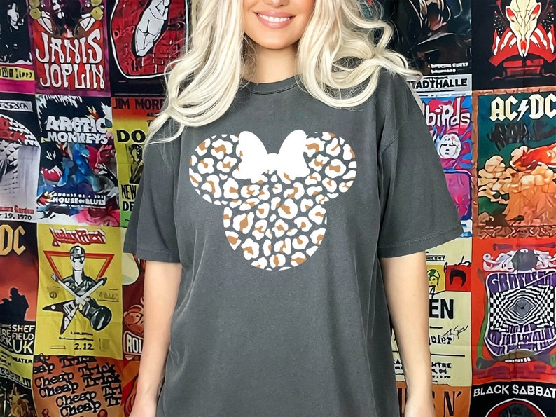 Peut inclure: Un t-shirt gris fonc&eacute; avec un motif de t&ecirc;te de Minnie Mouse en imprim&eacute; l&eacute;opard brun et blanc.