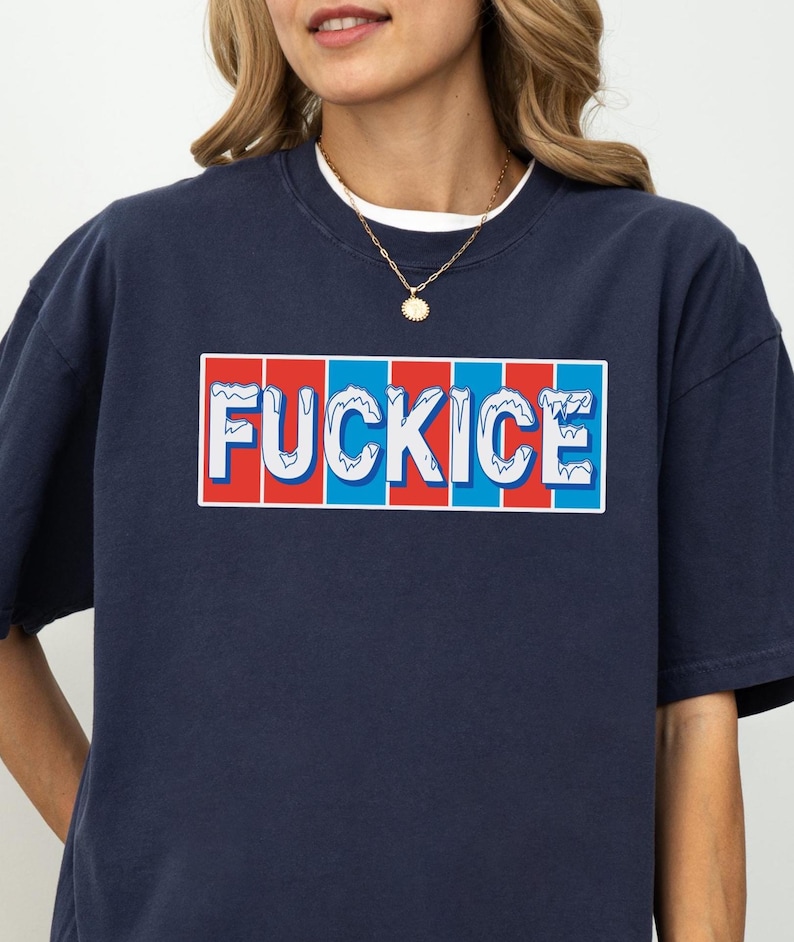 以下が含まれることがあります： 長方形のデザインで「FUCKICE」という言葉が入ったネイビーブルーのスウェットシャツ。テキストは白で、赤と青のストライプの背景があります。スウェットシャツは白いクルーネックの襟と金のネックレスが付いています。