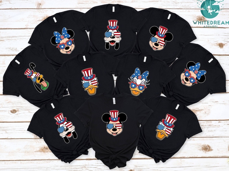 May include: Nine black t-shirts with different Disney characters wearing red, white, and blue patriotic hats and sunglasses. The characters include Mickey Mouse, Minnie Mouse, Donald Duck, Goofy, and Daisy Duck.