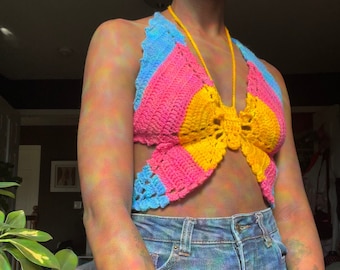 Puede incluir: Un top halter tejido a crochet con un diseño de mariposa en rosa, amarillo y azul.