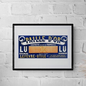 Peut inclure: Une publicité vintage encadrée pour les gaufrettes "Paille d'Or", avec un fond bleu, des lettres dorées et une représentation des gaufrettes. Le texte indique "Gaufrette au jus de framboise" et "Lefevre-Utile".