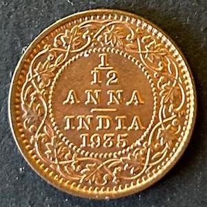 May include: A copper-colored Indian coin with a floral design around the edge. The coin reads "1/2 ANNA INDIA 1925".