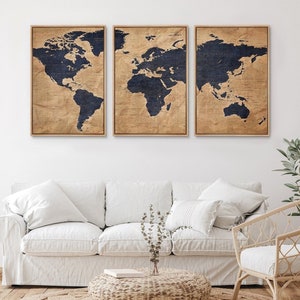 May include: A set of three framed world maps with a vintage, distressed look. The maps are printed on a beige background with dark blue continents. The frames are a light wood color.