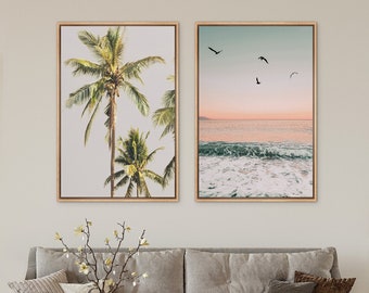 May include: Two framed prints, one with a palm tree and the other with a sunset over the ocean. The palm tree print has a light background and the ocean print has a pink and orange sunset.