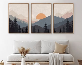 May include: Three framed prints of a mountain landscape with a sunset. The prints are in a minimalist style with a muted color palette of blues, grays, and pinks. The middle print features a large orange sun.