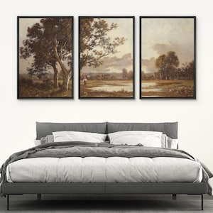 May include: Three framed landscape paintings with black frames. The artwork depicts trees, fields, and a body of water under a cloudy sky. The color palette is dominated by earth tones, creating a serene atmosphere.