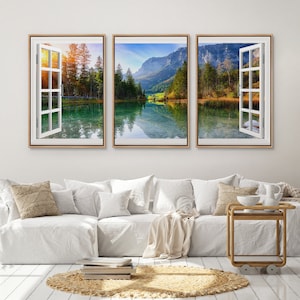 May include: Three framed prints of a scenic lake view through open windows. The lake is surrounded by trees and mountains, with a reflection of the sky and mountains in the water.