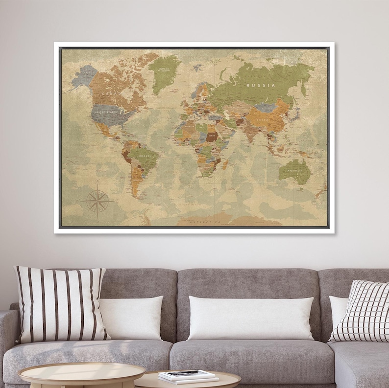 Puede incluir: Un mapa del mundo enmarcado con una est&eacute;tica vintage. El mapa presenta una paleta de colores apagados de verdes, marrones y beiges, con fronteras y etiquetas de pa&iacute;ses. Se ve una rosa de los vientos. El mapa est&aacute; enmarcado en un borde blanco con un borde interior negro.