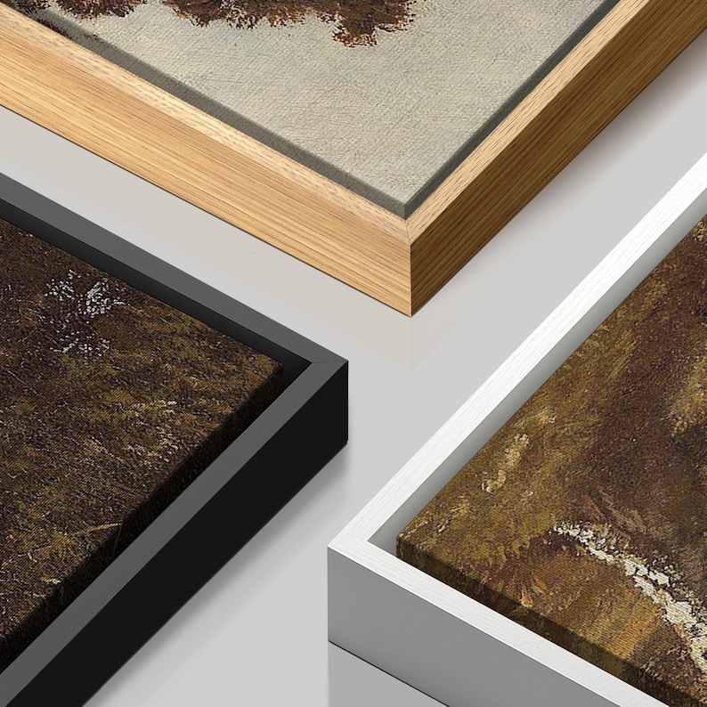 May include: Close-up of three framed canvas art prints. One frame is natural wood, another is black, and the third is white. The artwork features a landscape painting with brown and green tones.