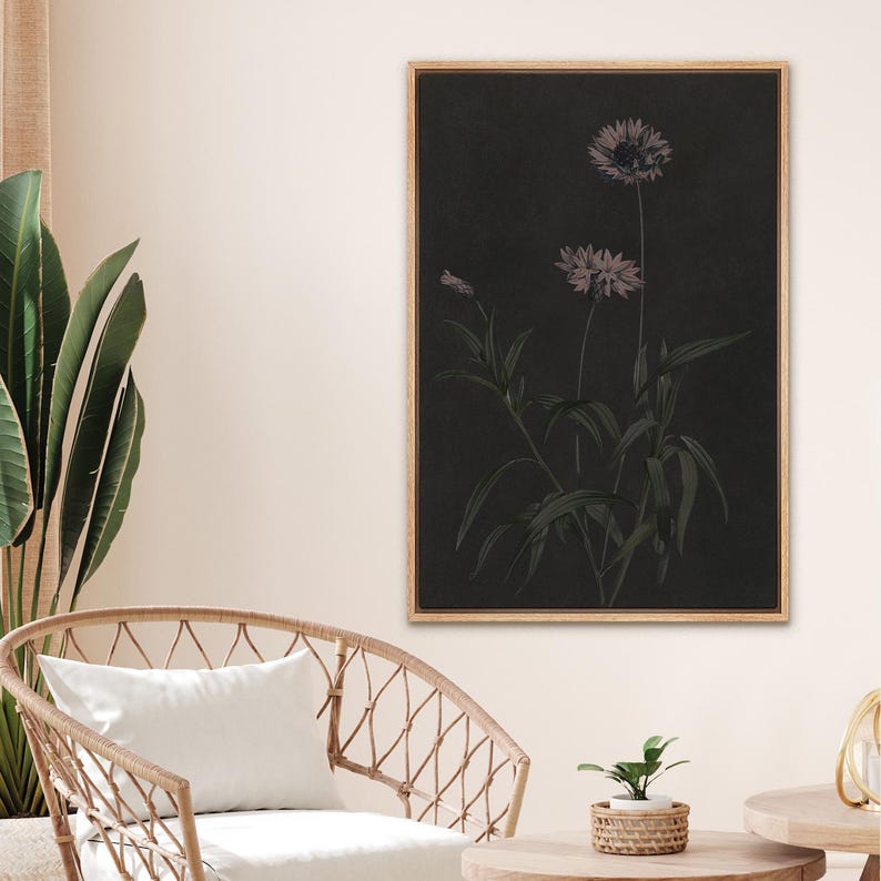 Puede incluir: Una impresi&oacute;n bot&aacute;nica enmarcada con un fondo oscuro, que presenta una ilustraci&oacute;n detallada de flores y hojas en tonos grises y morados. La obra de arte est&aacute; enmarcada en un marco de madera marr&oacute;n claro, a&ntilde;adiendo un toque de elegancia natural.