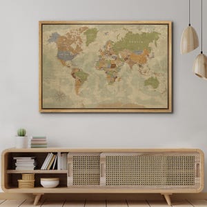 Puede incluir: Un mapa del mundo enmarcado con una est&eacute;tica vintage. El mapa presenta una representaci&oacute;n detallada de continentes y pa&iacute;ses en tonos apagados de verde, marr&oacute;n y azul. El marco de madera a&ntilde;ade un toque cl&aacute;sico.