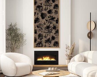 May include: A large, rectangular framed artwork featuring a floral pattern in shades of black and gray against a tan background. The artwork hangs above a fireplace in a modern living room setting. The room includes white furniture and a wooden coffee table.