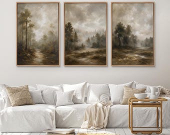 May include: A set of three framed wall art prints featuring a moody, atmospheric forest landscape in muted earth tones of brown, beige, and grey. Each rectangular print depicts a misty woodland scene with tall trees and a soft, cloudy sky.
