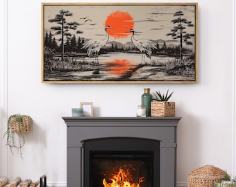 May include: A framed canvas print featuring a serene landscape with two cranes standing in water, a vibrant orange sun, and silhouetted trees. The artwork has a gold frame and evokes a sense of tranquility.
