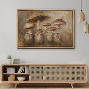 May include: A framed canvas art print featuring a group of owls under large mushrooms. The artwork has a warm, earthy color palette with brown, beige, and tan tones. The owls have detailed feathers and expressive eyes, creating a whimsical forest scene.