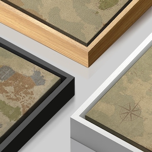 Puede incluir: Primer plano de tres impresiones en lienzo enmarcadas con un dise&ntilde;o de mapa del mundo vintage. Los marcos son de madera natural, negro y blanco. El mapa tiene una paleta de colores neutros con una rosa de los vientos.