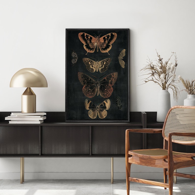 May include: A black and white framed print of five butterflies with gold and orange accents on a dark background.