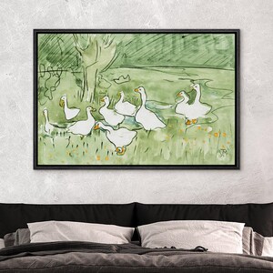 May include: Watercolor painting of a flock of white geese in a green field with a tree in the background. The artwork is framed in a black rectangular frame. The geese have yellow beaks and feet. The painting has a whimsical, illustrative style.